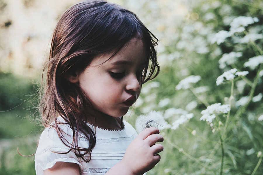 a girl playing with a dandelion