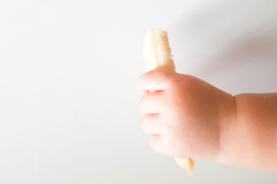 baby holding a piece of banana